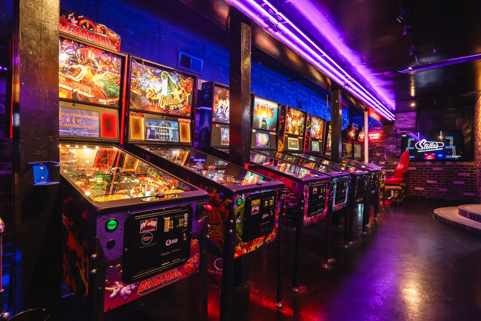 The row of pinball machines at Stella's, lit purple and green